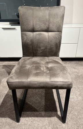 Der Schwingstuhl „Valencia 1“ in der Farbe „Vintage Anthrazit“ mit schwarzen Metallbeinen steht auf einem Teppich vor weißen Schränken.