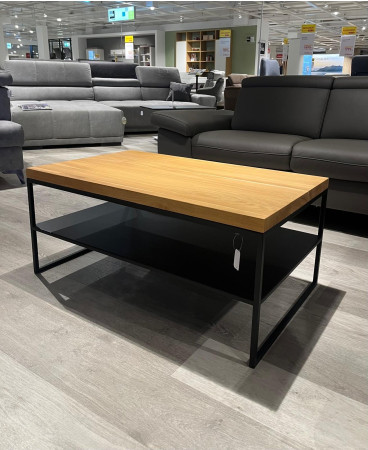 Couchtisch Axel 3 aus massiver Wildeichenplatte, Metall schwarz, im Showroom vor Sofas ausgestellt.