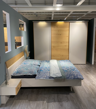 Modernes Schlafzimmer mit einem „Mondo Easymax 200“-Bett, blauer Bettwäsche, Wandregalen und einem Kleiderschrank mit LED-Beleuchtung.
