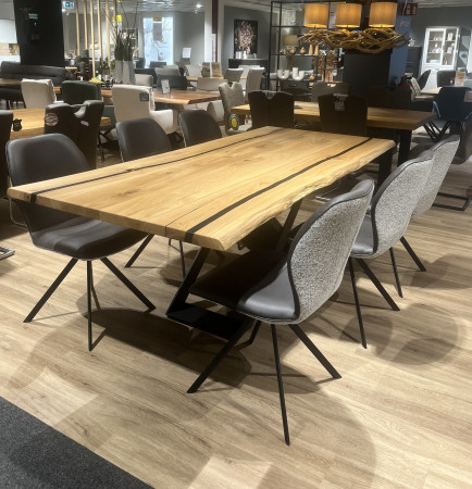 Die Esszimmergarnitur „Valmondo Esgo“ mit Mikrofaser-Stühlen und einem Tisch aus Massiveiche ist im Ausstellungsraum auf einem Holzboden ausgestellt.