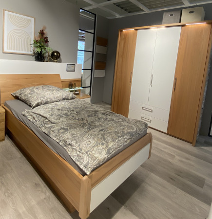 Modernes Schlafzimmer mit dem „Mondo Comfort Plus“-Schlafzimmer-Set von Komfort, gemusterter Bettwäsche, einem Kleiderschrank und Wanddekoration.