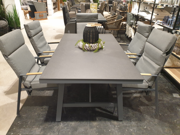 Das Esszimmer-Set „Grado“ umfasst vier gepolsterte graue Stühle und einen quadratischen Tisch mit einer Tischdekoration darauf.