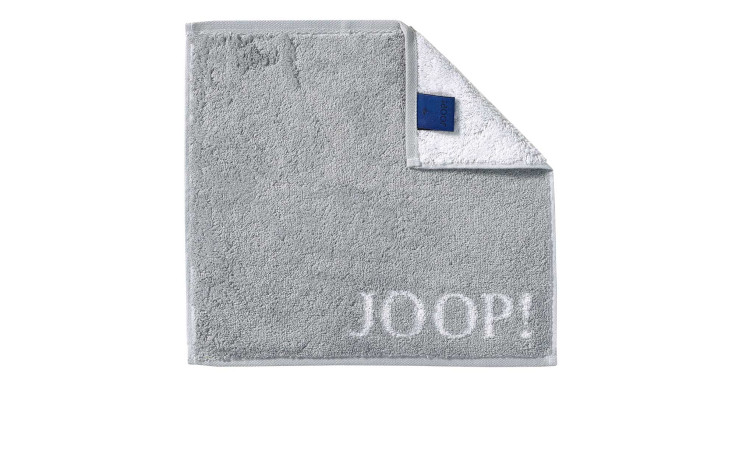 Hellgraues JOOP! Seiftuch Classic 30x30 cm, eine Ecke gefaltet, so dass das blaue Joop-Etikett im Inneren sichtbar wird.