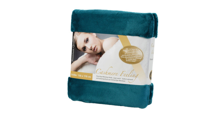 Eine gefaltete tealfarbene Gözze Wohndecke Premium Cashmere Feeling 130 x 170 cm mit einem Etikett, das eine Frau zeigt.