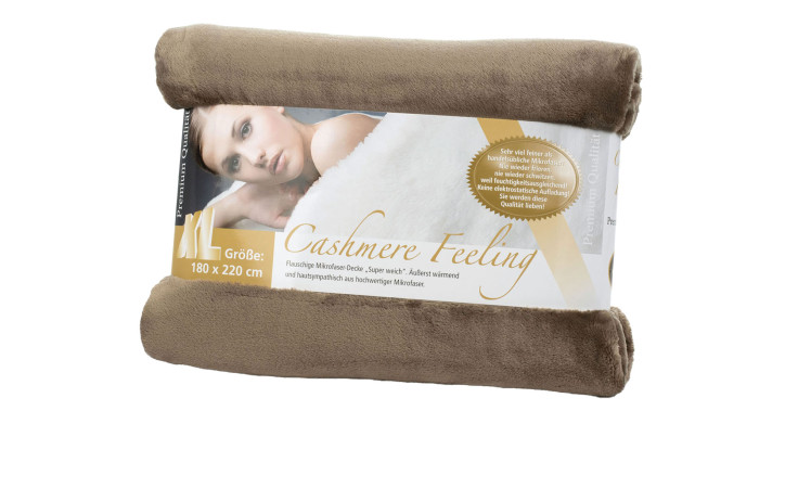 Eine Gözze Wohndecke Premium Cashmere Feeling, 180x220 cm, taupe, gerollt mit Etikett, das eine darin eingewickelte Frau zeigt.