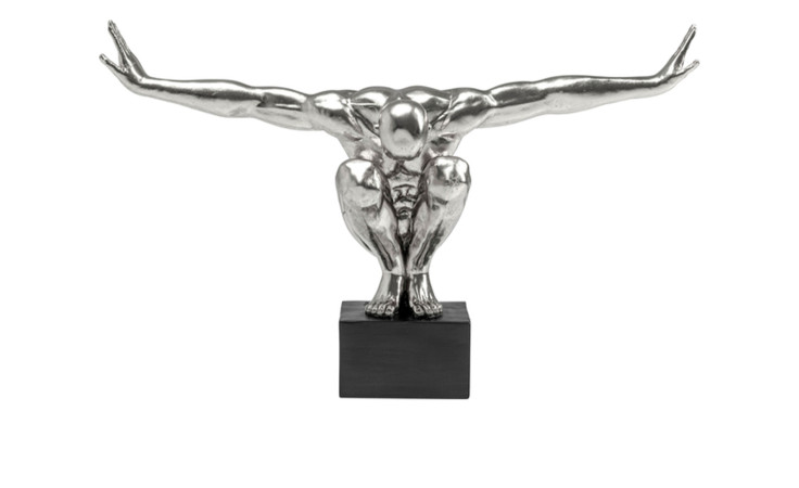 Das Kare Deko-Objekt Athlet ist eine silberne hockende Figur mit ausgestreckten Armen auf einem schwarzen Sockel, modernes Dekor.