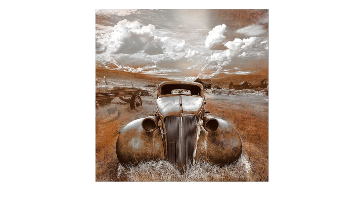 Das Pro-Art Alubild Lost Car 100 x 100 cm zeigt ein verrostetes Auto auf einem Feld unter Wolken, Gras und fernen Gebäuden.