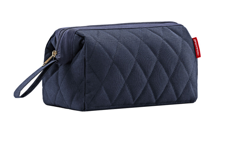 Die Reisenthel Kulturtasche Travelcosmetic in Rhombus Midnight Gold hat ein 3D-Design, einen Reißverschluss, eine Handschlaufe und einen roten Anhänger.