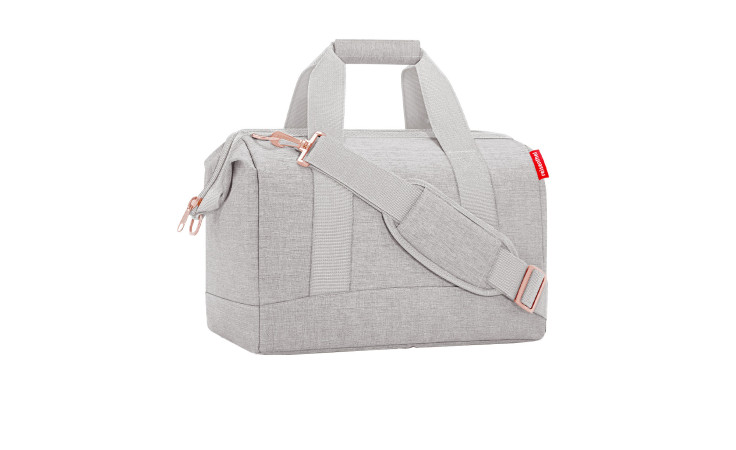 Die Reisenthel Reisetasche Allrounder M ist ein hellgrauer Seesack aus recyceltem Polyester mit Griffen, Riemen und rotem Seitenanhänger.