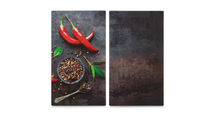 Zwei mehrfarbige Herdabdeck-/Schneideplatten: eine mit Chili-Pfeffer-Muster, eine mit schlichter dunkler Glasoberfläche.
