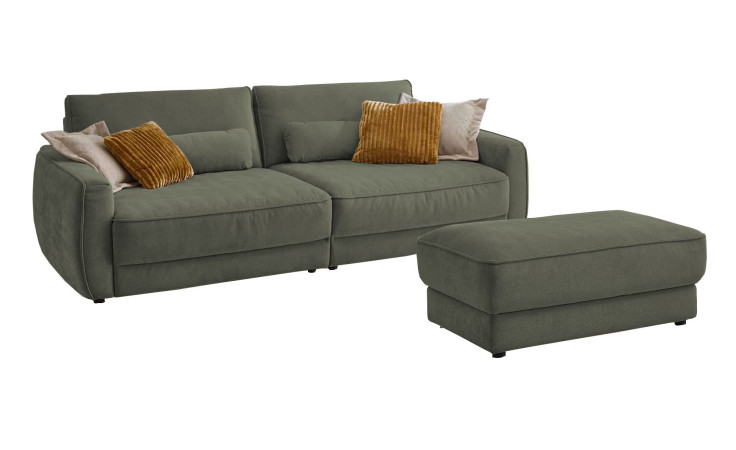 Komfort-Big Sofa planoform Cochem in der Farbe Grün mit mehreren Kissen, zwei davon sind braun, und der passende Hocker dazu