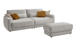 Komfort-Big Sofa planoform Cochem in der Farbe Weiß mit mehreren Kissen, zwei davon sind braun, und der passende Hocker dazu