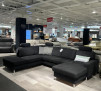 Das Ecksofa Planoform Nizza mit Federkern und Kissen, ausgestellt in einem hellen, modernen Möbelausstellungsraum.