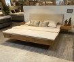 Bett mit Nachttischen (Freiburg 11) aus geölter Wildeiche mit Kopfteil in Cord-Beige, ausgestellt in einem stilvollen Schlafzimmer.