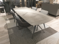 Tischgruppe „Cliff/Andria“: moderner Tisch aus grauem Geflecht, 6 Stühle mit Olefin-Kissen, auf einem gemusterten Teppich.