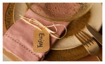 Nahaufnahme der beigen Dekoration mit rosa Serviette, For You Anhänger und goldenem Besteck auf Leonardo Teller Matera 22,5 cm.