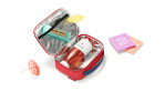 Die Reisenthel Kühltasche Thermocase ist eine rote Polyester-Lunchbag mit Saftflasche, Snackbar, Regenschirm und Schokoriegel.