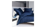 Mako-Satin Kissenbezug Colors in der Größe 40 x 40 cm und in der Farbausführung jeansblau, auf einem Bett bezogen mit der passenden Bettwäsche und weitere Kissen