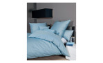 Mako-Satin  Kissenbezug Colors, in der Größe 80 x 80 cm und in der Farbausführung blau, auf einem Bett bezogen mit der passenden Bettwäsche und weiteren Kissen