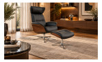Sessel mit Hocker „Space 5800“ aus modernem schwarzem Leder auf einem Teppich in einem stilvollen, sonnendurchfluteten Wohnzimmer.