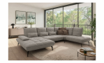 Modernes Wohnzimmer mit der Komfort-Wohnlandschaft „vito Ticona Plus“ von Vito, einem runden Teppich, einem Couchtisch, Fenstern und Pflanzen.