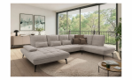 Modernes Wohnzimmer mit der Komfort-Wohnlandschaft „vito Ticona Plus“ von Vito, einem runden Teppich, einem Couchtisch und großen Fenstern.
