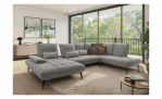 Modernes Wohnzimmer mit dem Sofa „Vito Ticona Plus“ mit Sitztiefenverstellung, braun-grauen Kissen und großen Fenstern.