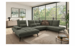 Modernes Wohnzimmer mit der „Vito Komfort-Wohnlandschaft Ticona Plus“, einem runden Teppich, einem Couchtisch und Blick in die Natur.