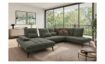 Modernes Wohnzimmer mit der Modulsofa-Garnitur „Vito Ticona Plus“ von Vito, einem runden Teppich und großen Fenstern, die einen malerischen Ausblick bieten.