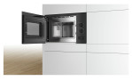 BOSCH Einbau-Mikrowelle BFL520MB0 mit Edelstahl-Innenraum in einer modernen weißen Küche, Tür auf Holzboden geöffnet.