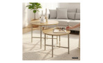 Eine Hand stellt Gläser auf den kleineren Tisch eines Couchtisch Delia-Sets, das aus zwei runden Holzplatten und Metallbeinen besteht.