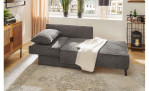 Schlafsofa Ravensburg in der Farbe Grau in Liegeform in einem Zimmer