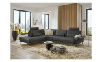 Komfort-Ecksofa plano|FORM Formello, in der Farbausführung Anthrazit, in einem Raum stehend mit der klappbaren Armlehne und mit Kissen und Kopfstütze