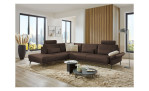 Komfort-Ecksofa plano|FORM Formello, in der Farbausführung Braun, in einem Raum stehend mit der klappbaren Armlehne und mit Kissen und Kopfstütze