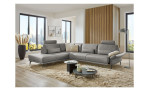 Komfort-Ecksofa plano|FORM Formello, in der Farbausführung Grau, in einem Raum stehend mit der klappbaren Armlehne und mit Kissen und Kopfstütze