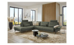 Komfort-Ecksofa plano|FORM Formello, in der Farbausführung Grün, in einem Raum stehend mit der klappbaren Armlehne und mit Kissen und Kopfstütze