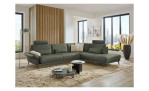 Komfort-Ecksofa plano|FORM Formello, in der Farbausführung Grün, in einem Raum stehend mit der klappbaren Armlehne und mit Kissen und Kopfstütze