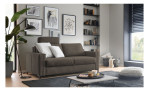 Modernes Wohnzimmer mit einem braunen Hukla Komfort-Schlafsofa „Pickering“, gerahmten Kunstwerken, Regalen, Pflanzen und einem niedrigen Couchtisch.