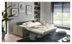 Ein graues „Basis“-Schlafsofa „Pickering“ von Hukla steht in einem modernen Wohnzimmer mit Kunstwerken, Regalen und Fenstern.