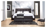 Basis-Boxspringbett Premium Magnifique mit einem Bezugsstoff in Anthrazit. Auf einem dekorierten Hintergrund