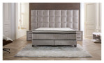 Basis-Boxspringbett Magnum Extra Grande in einem grauen Bezugsstoff. Auf einem dekoriertn Hintergrund