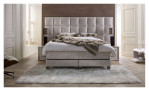 Basis-Boxspringbett Magnum Extra Grande in einem grauen Bezugsstoff. Auf einem dekoriertn Hintergrund
