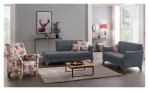 Modernes Wohnzimmer mit der Komfort-Sitzgruppe „MONDO Quadra“ von Mondo, einem Sessel mit Blumenmuster, einem Teppich, einem Couchtisch und Kunstobjekten.