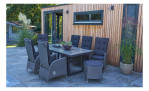 Terrasse mit LC Garden Gartensessel „Barcelona Komfort“, acht Stühlen, Kissen und Pflanzen neben einem modernen Holzbau.