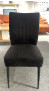 Der Stuhl „Klaus“ aus schwarzem Webstoff mit vertikalen Nähten, BHT 47 x 97 x 65 cm, steht auf einem grauen Teppichboden.
