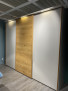 Dreitüriger Kleiderschrank „Mondo Easymax 200“ mit mittlerer Holzverkleidung und hellgrauen Seitenwänden in einer modernen Einrichtung.