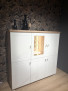Hochschrank „Vito Idamo“ in Tonweiß matt, 135 × 132 × 40 cm, beleuchtetes Glasregal, Dekor „Alteiche“, Akzente durch Blumentapete.