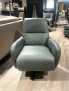 Ein moderner grauer Sessel „Planoform Tivoli“ mit Kaltschaum-Polsterung steht auf einem Holzboden, umgeben von Sofas.