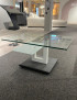 Couchtisch 7460HK-060O-09 mit Glasplatte, U-förmiges Gestell auf Teppichboden; in der Nähe sind Pfotenabdrücke zu sehen.