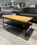 Couchtisch Axel 3 aus massiver Wildeichenplatte, Metall schwarz, im Showroom vor Sofas ausgestellt.